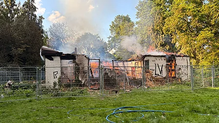 Rietgedekte, leegstaande woonboerderij staat in brand. De begane grond is nog zichtbaar. Er staan hekken omheen.